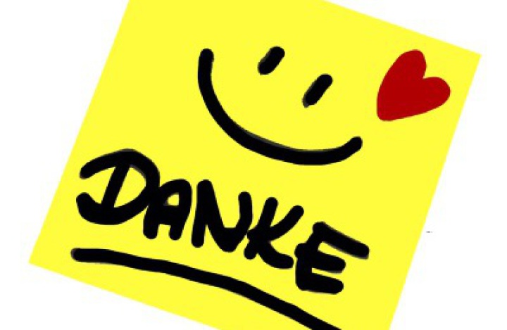 Gelber Notizzettel mit der Aufschrift "Danke", einem lachenden Gesicht und einem roten Herz